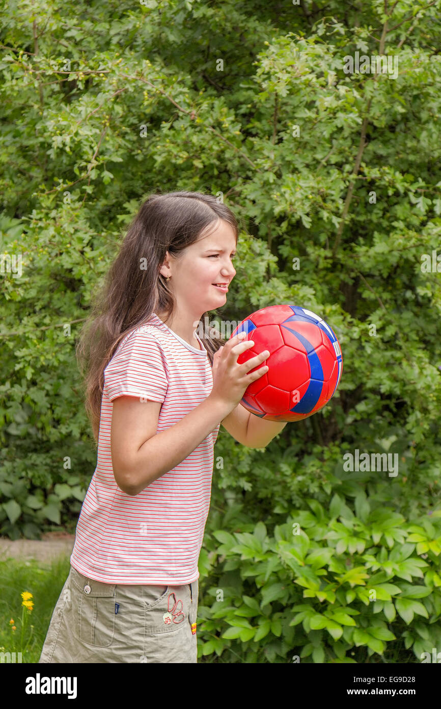 Chico Chica jugando con una pelota de fútbol en el jardín Foto de stock