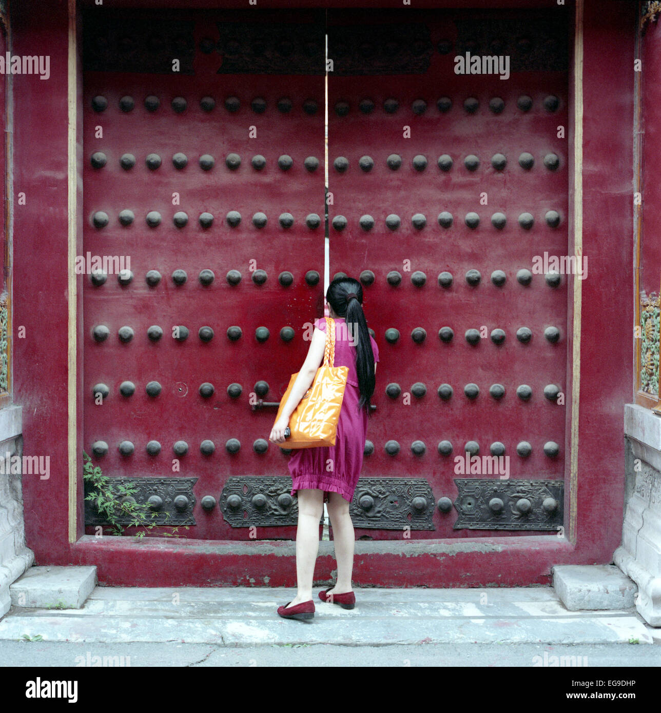 Mujer peeking a través de la puerta, la Ciudad Prohibida, Beijing, China Foto de stock