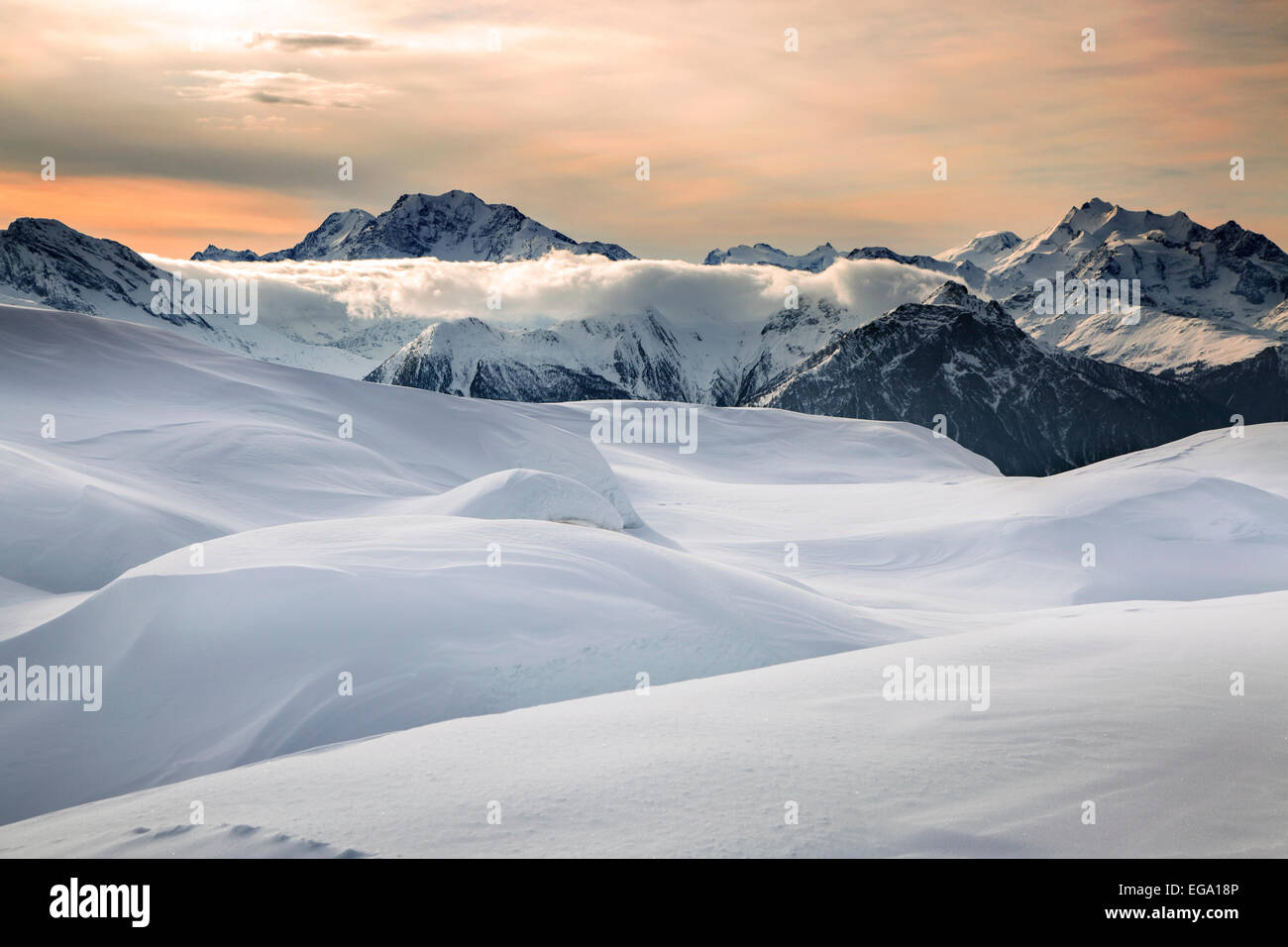 Puesta de sol sobre las montañas alpinas cubiertas de nieve en invierno en los Alpes Suizos en Wallis / Valais, Suiza Foto de stock