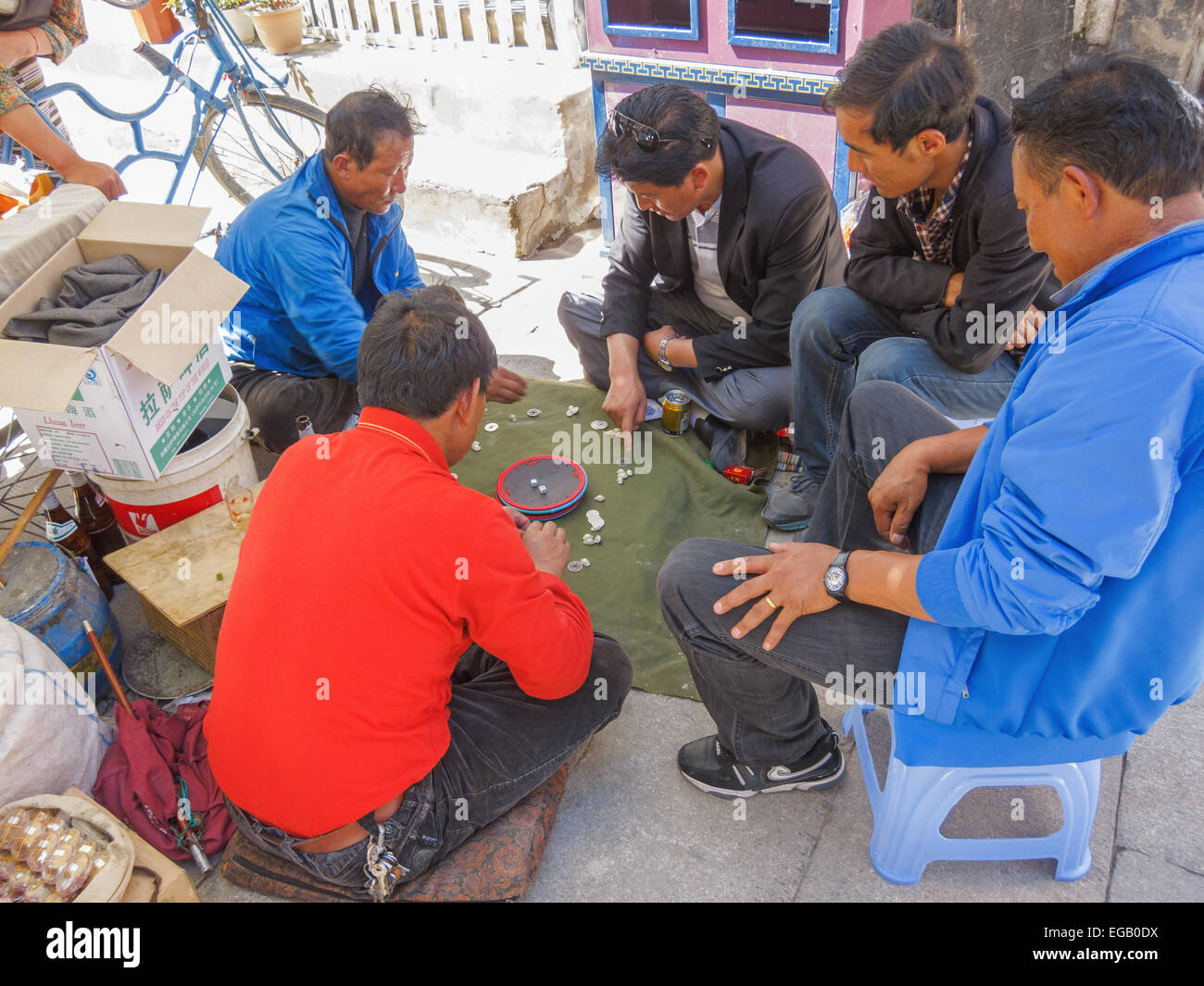 Los hombres tibetano jugar un juego de dados con monedas y pequeñas conchas como un pasatiempo en la calle en Lhasa, Tibet, China Foto de stock