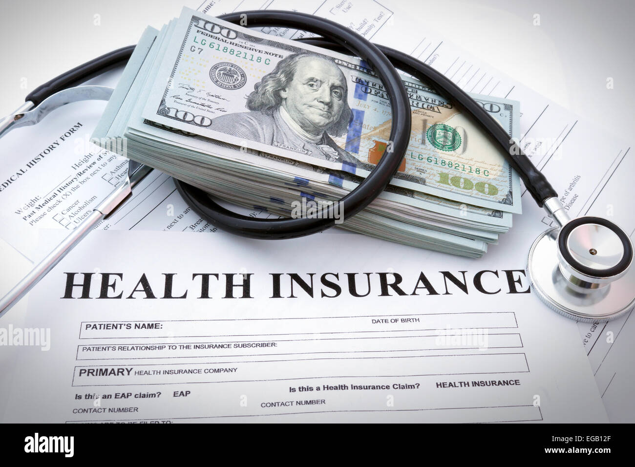 Formulario de seguro de salud con dinero y estetoscopio Foto de stock