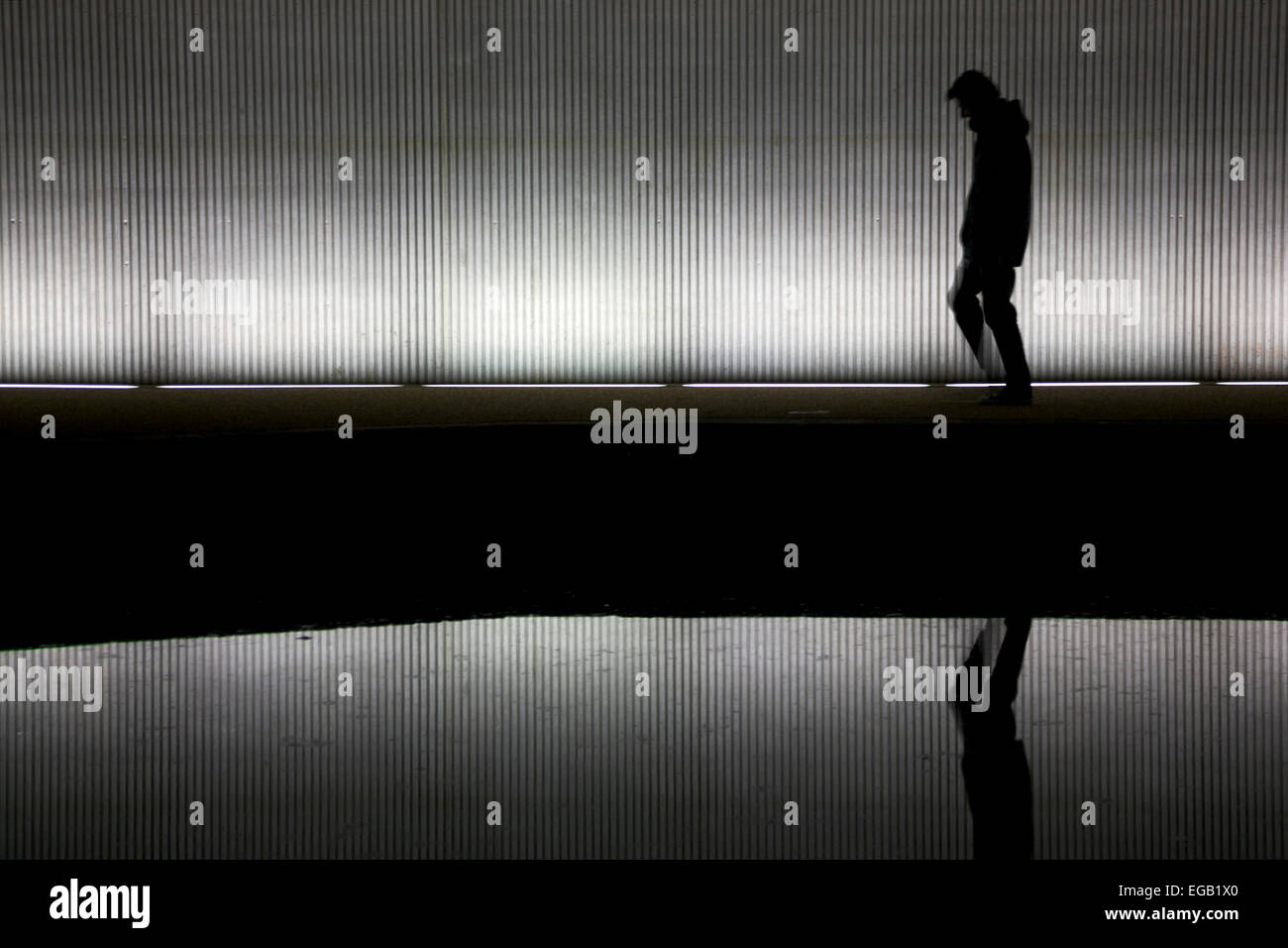 Hombre solitario caminando debajo de un puente/túnel Foto de stock