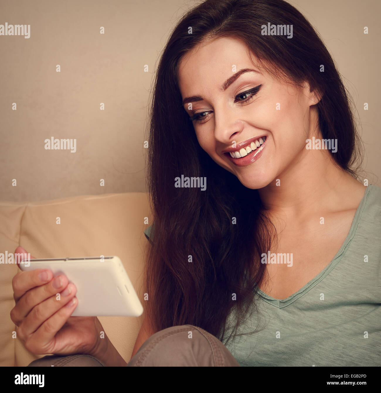 Hermosa mujer mirando en el teléfono móvil y sonriente. Retrato Vintage Foto de stock