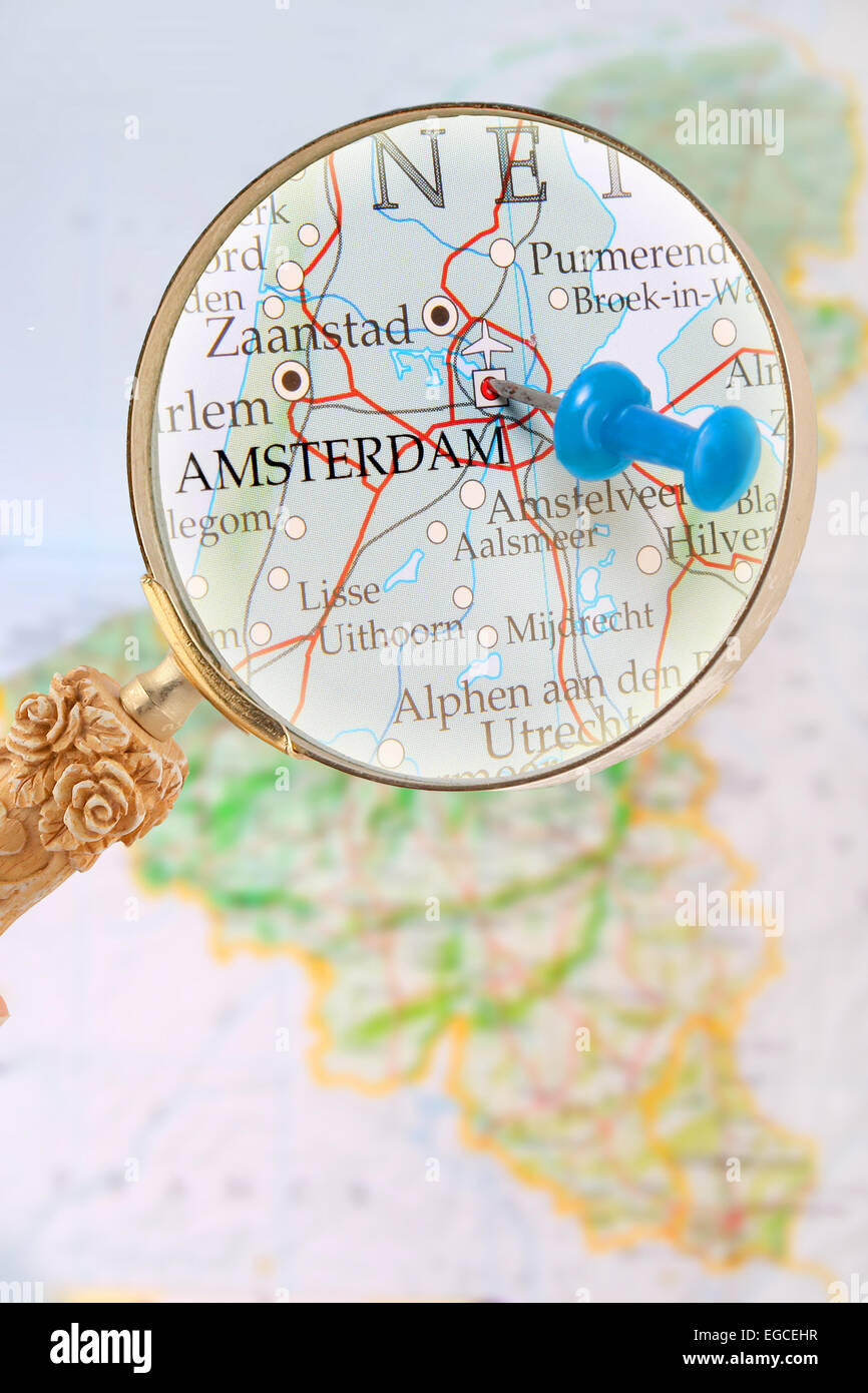 Tachuela azul en el mapa del Benelux con lupa mirando en Amsterdam, Holanda Foto de stock