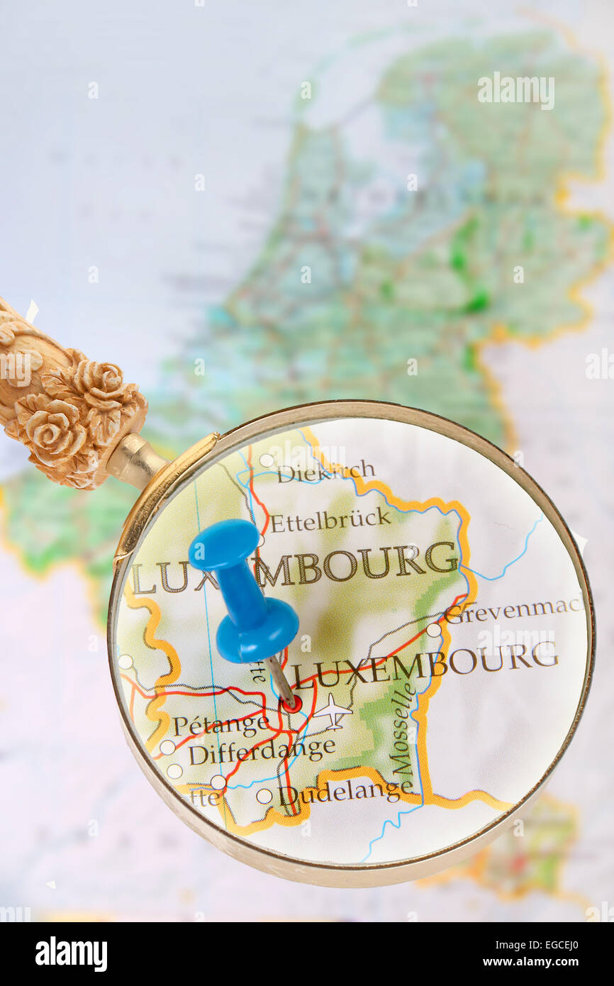 Tachuela azul en el mapa del Benelux con lupa mirando en Luxemburgo, Europa Foto de stock