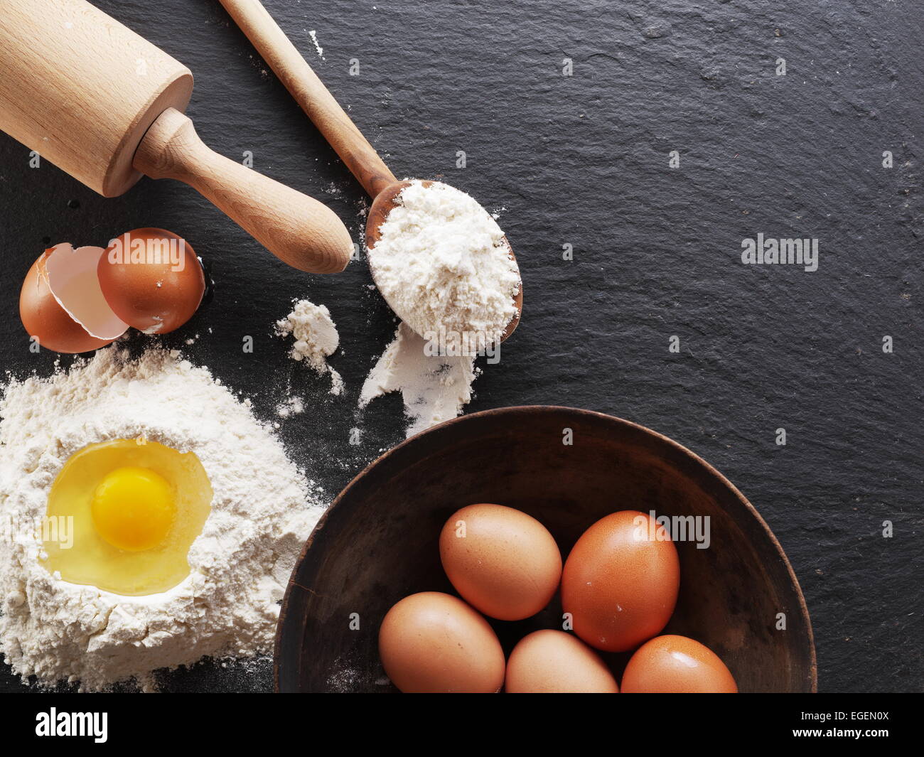 Preparación de la masa. Hornear ingredientes: huevo y harina en la placa negra. Foto de stock
