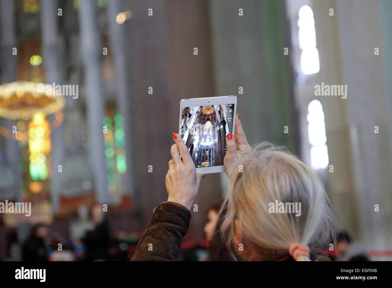 Mujer fotografías videos interior de la Sagrada Familia, Barcelona, utilizando un dispositivo de tipo tablet iPad. Experimentando digitalmente mundial Foto de stock