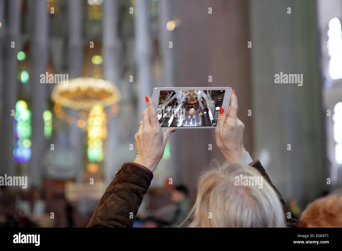 Mujer fotografías videos interior de la Sagrada Familia, Barcelona, utilizando un dispositivo de tipo tablet iPad. Experimentando digitalmente mundial Foto de stock