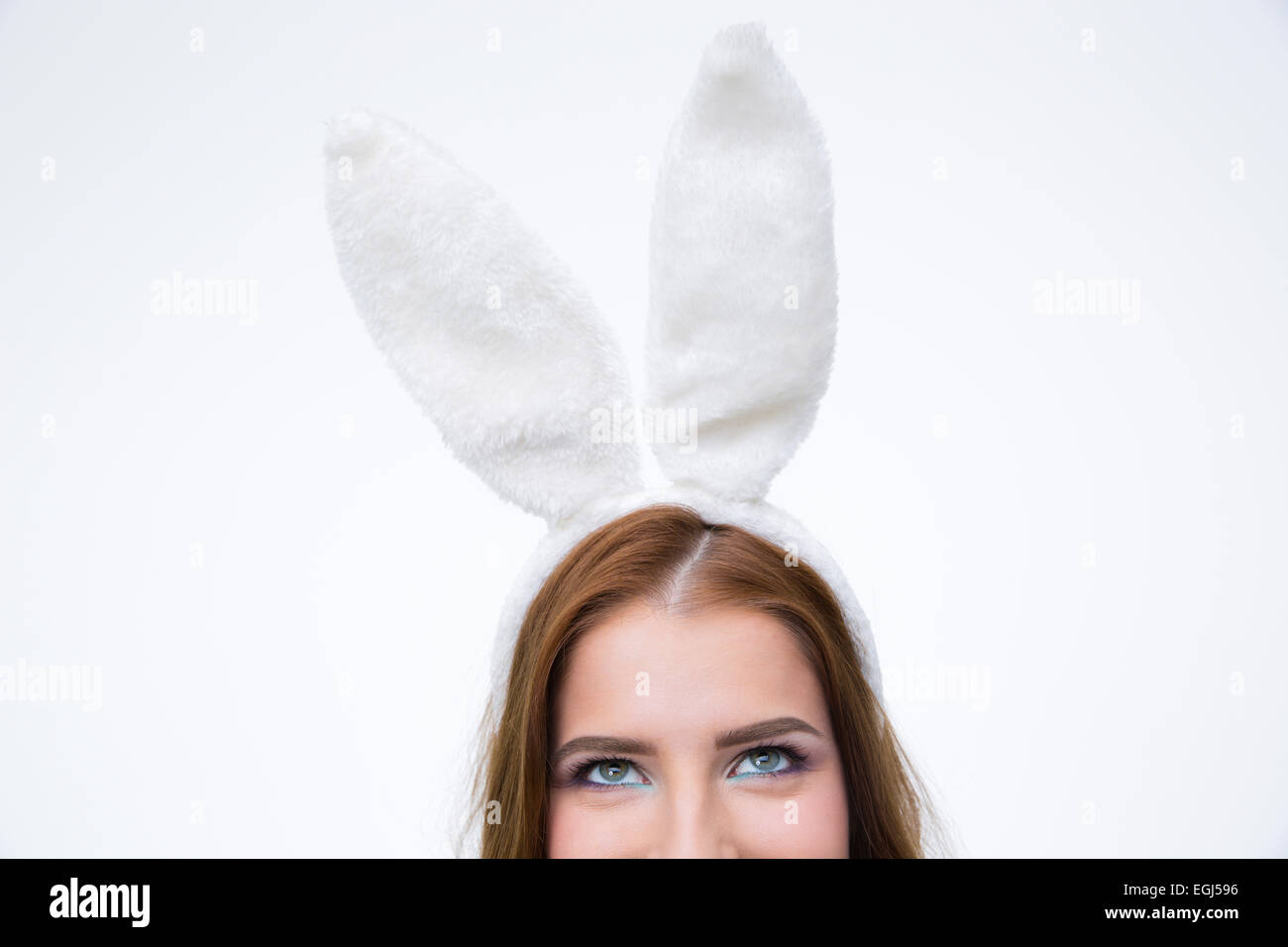 Imagen recortada de una mujer en orejas de conejo mirando hacia arriba sobre fondo gris Foto de stock
