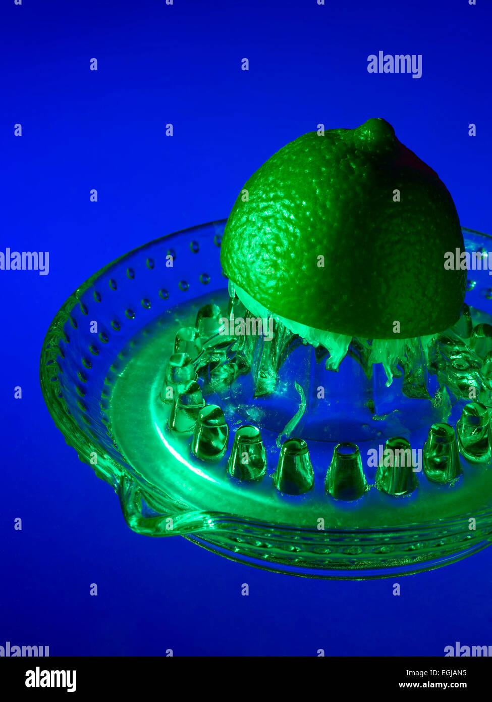 Lima y el jugo de limón en el exprimidor de vidrio Foto de stock