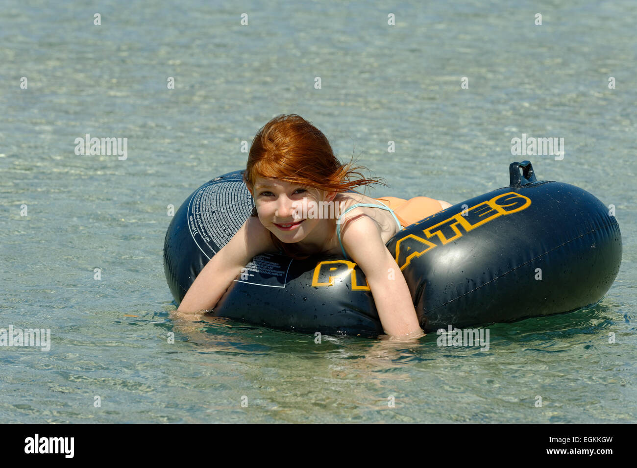 Una chica en grandes neumáticos flotantes en las aguas turquesas de la Bahía de Rondinara, costa sureste, Córcega, Francia Foto de stock