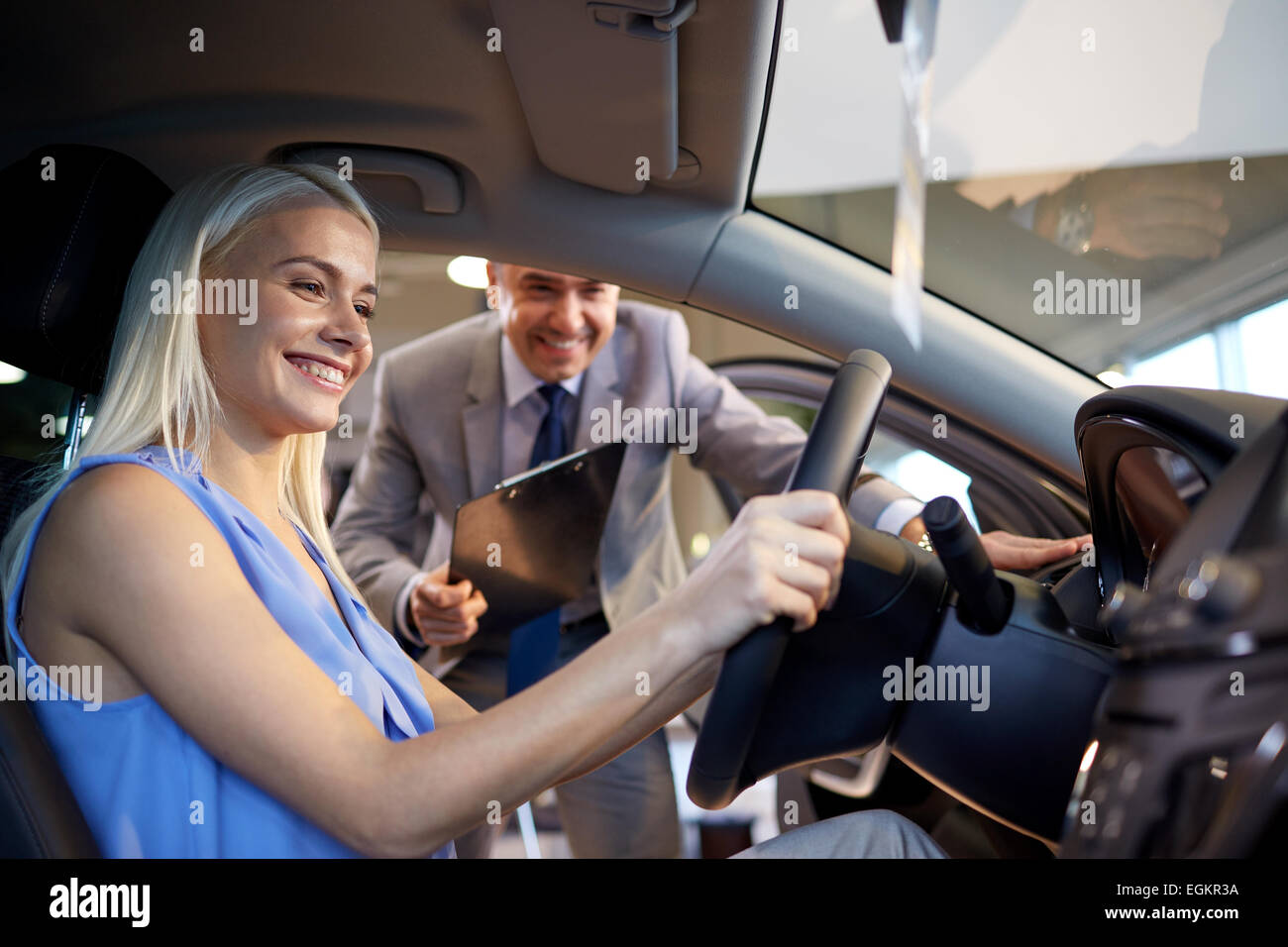 Mujer feliz con un concesionario de coches en auto show o salon Foto de stock