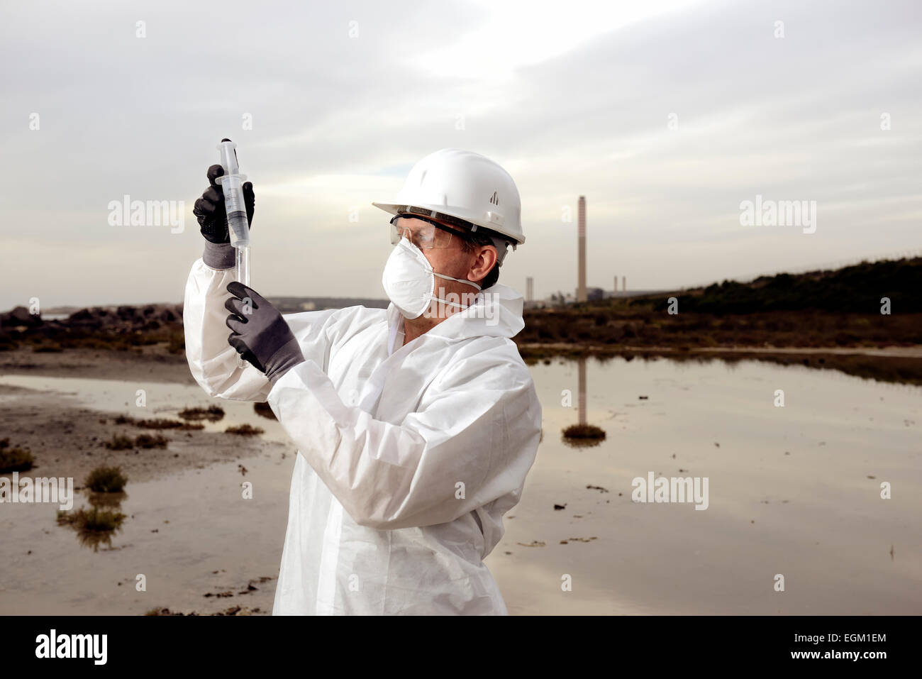 Traje de protección del trabajador en el examen en la contaminación del agua en la industria. Foto de stock