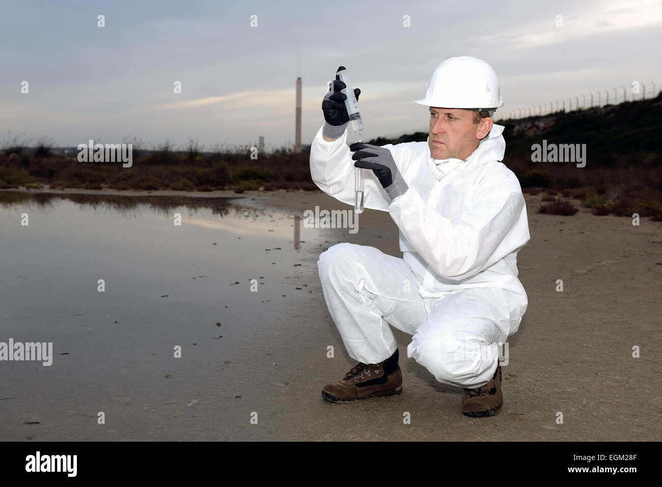 Traje de protección del trabajador en el examen en la contaminación del agua en la industria. Foto de stock