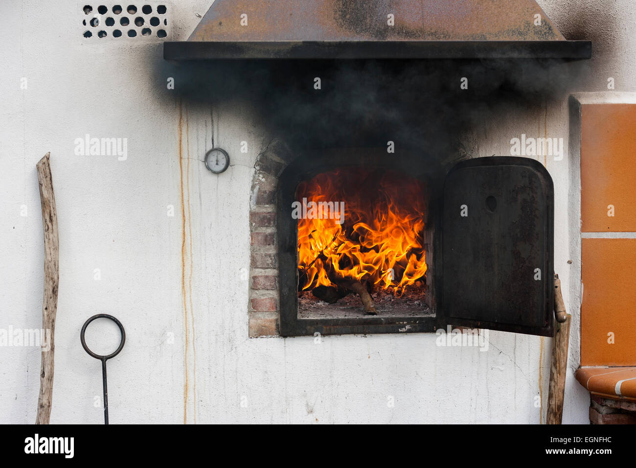 Horno de piedra con llamas dentro y humo negro que sale de la puerta  Fotografía de stock - Alamy
