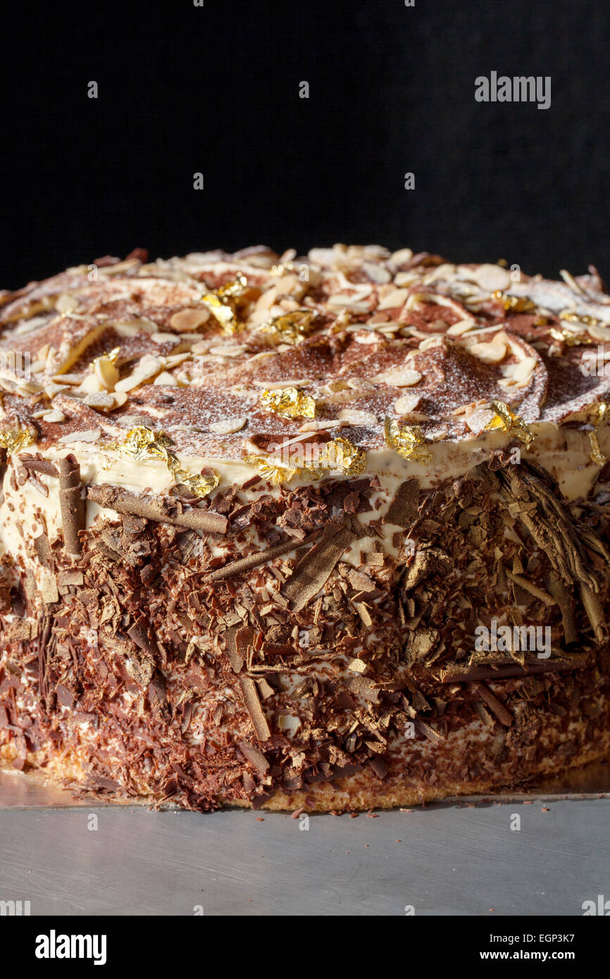 Tarta de chocolate de lujo rematada con almendras y hoja de oro Foto de stock