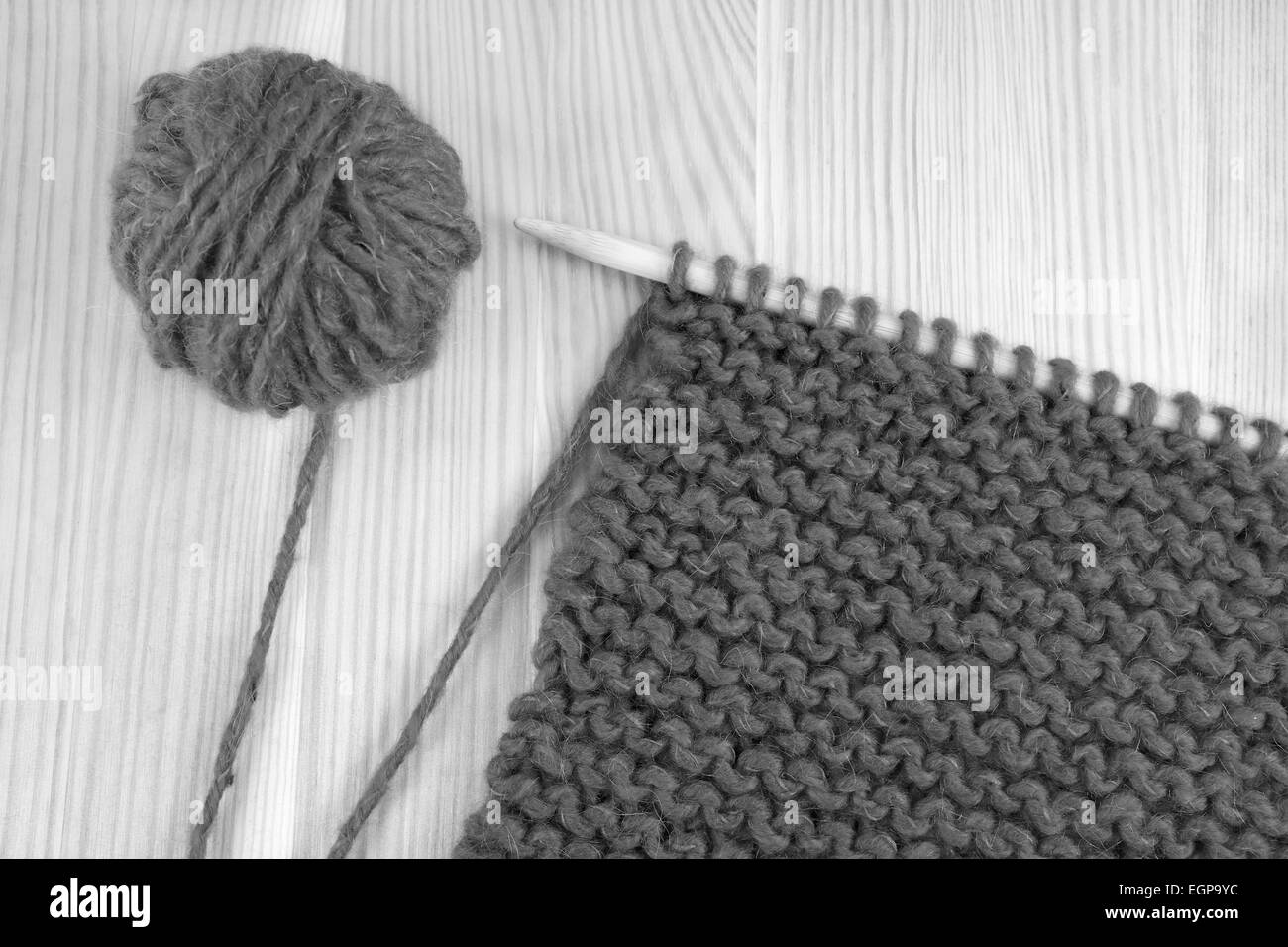 Bola de lana y garter stitch en una aguja de tejer - procesamiento monocromo Foto de stock