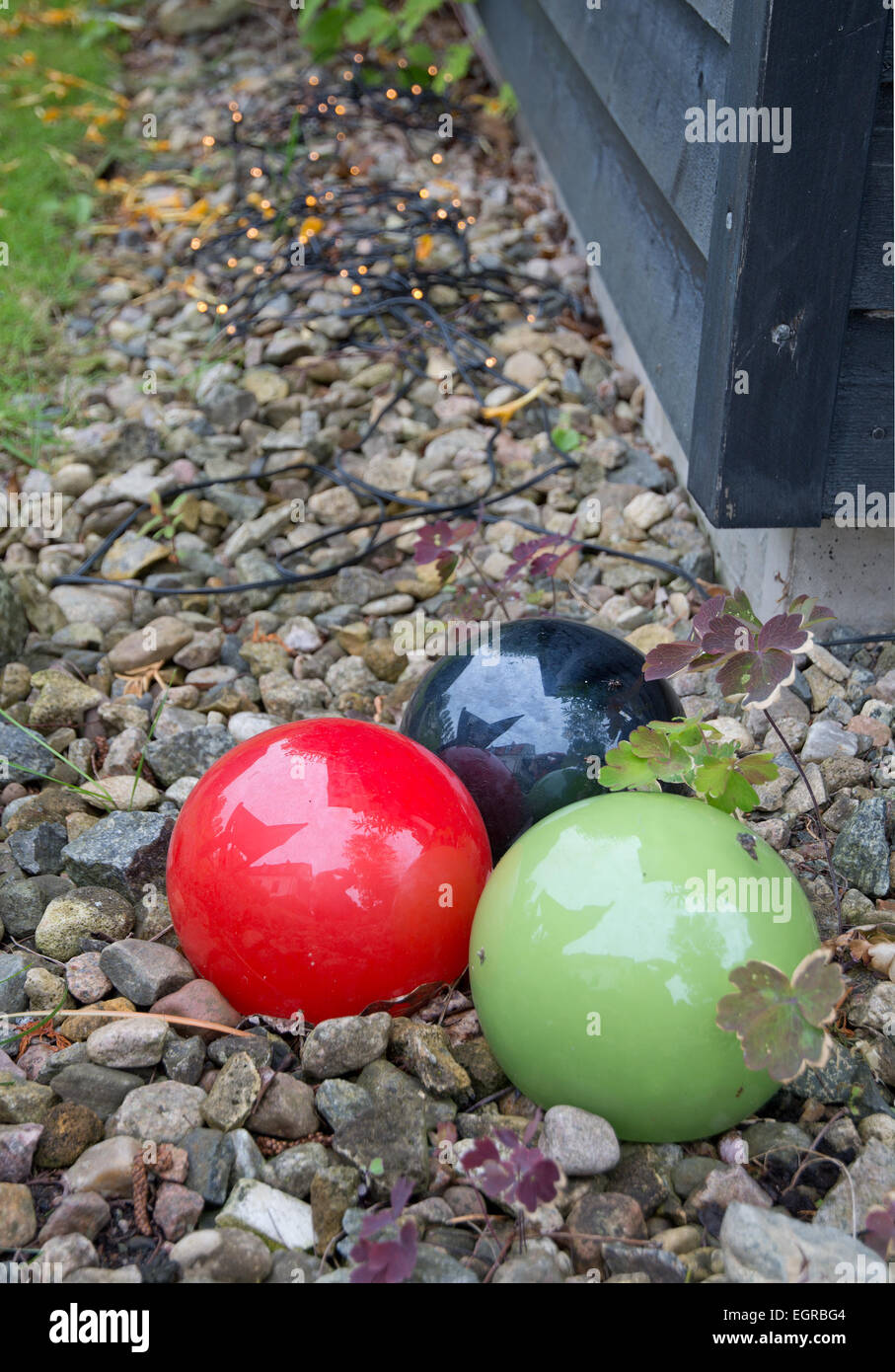 Decoración de jardines decoración roja, verde y negro bolas en la grava. Jardín verde en julio, Suecia. Foto de stock