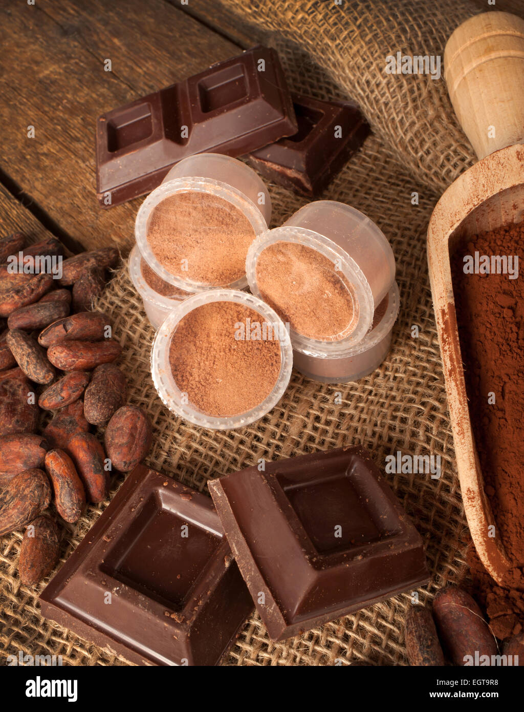 Cápsulas de chocolate con cacao en polvo, granos de cacao y trozos de