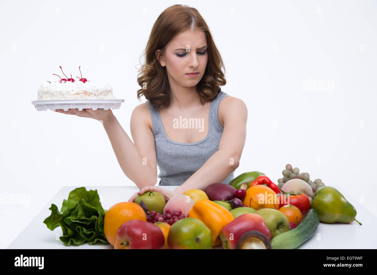 Mujer hace elección entre tartas y verduras saludables Foto de stock