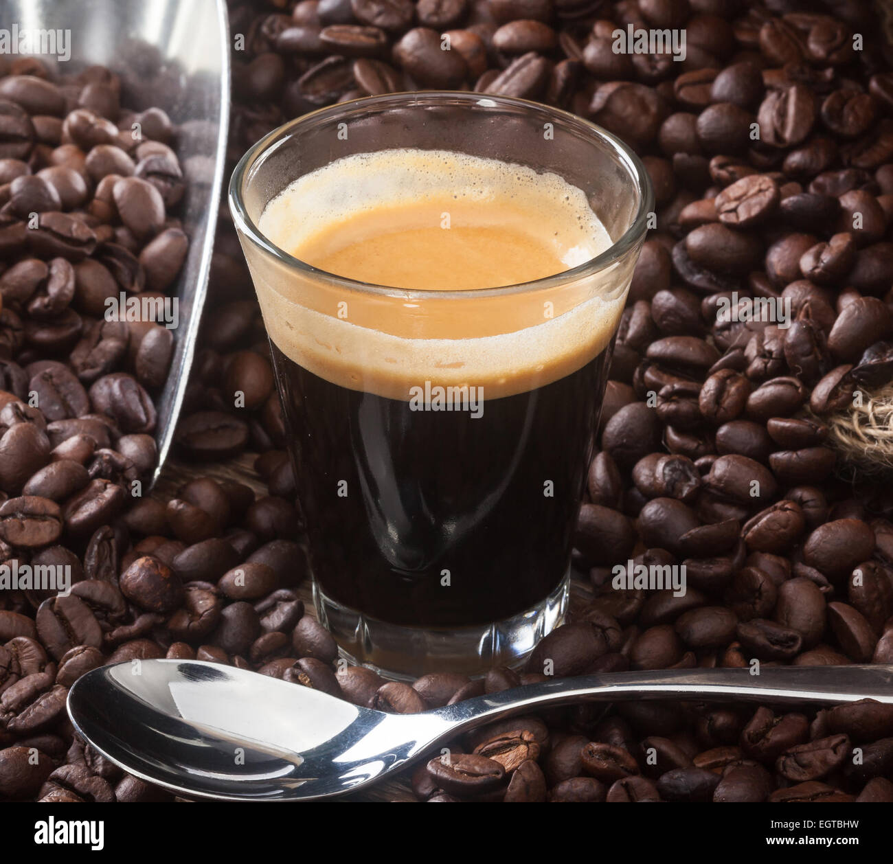 Café espresso en un vaso con granos de café sobre la mesa de madera. Foto de stock