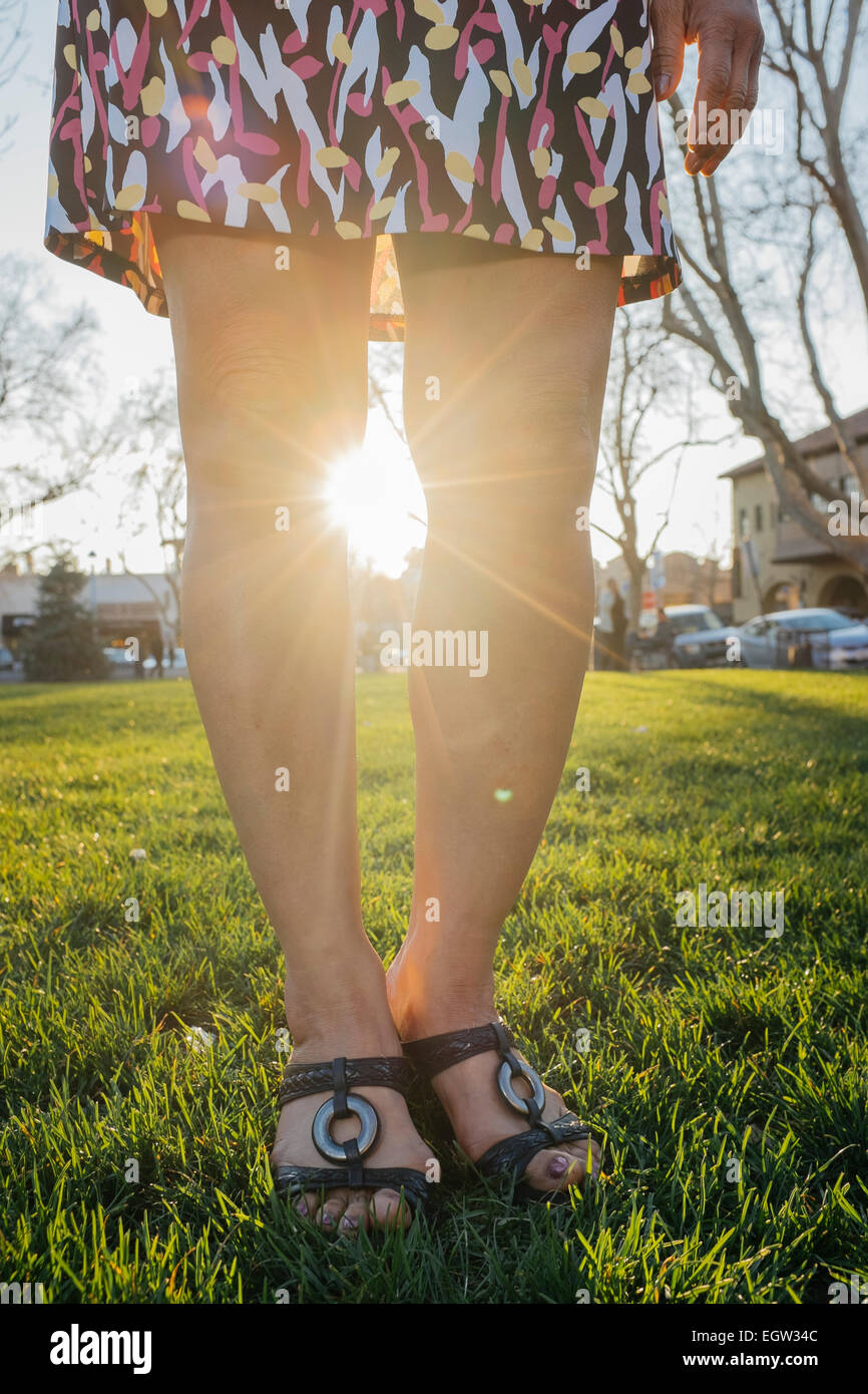 Las piernas de una mujer con el sol brillando entre ellos. Foto de stock