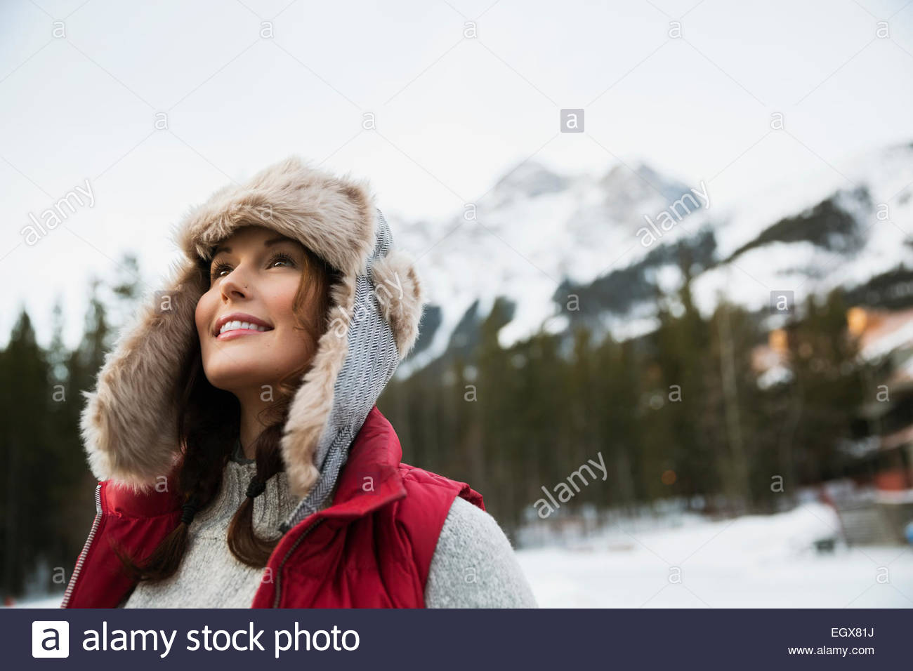 Curioso mujer mirando hacia arriba debajo de montañas nevadas Foto de stock