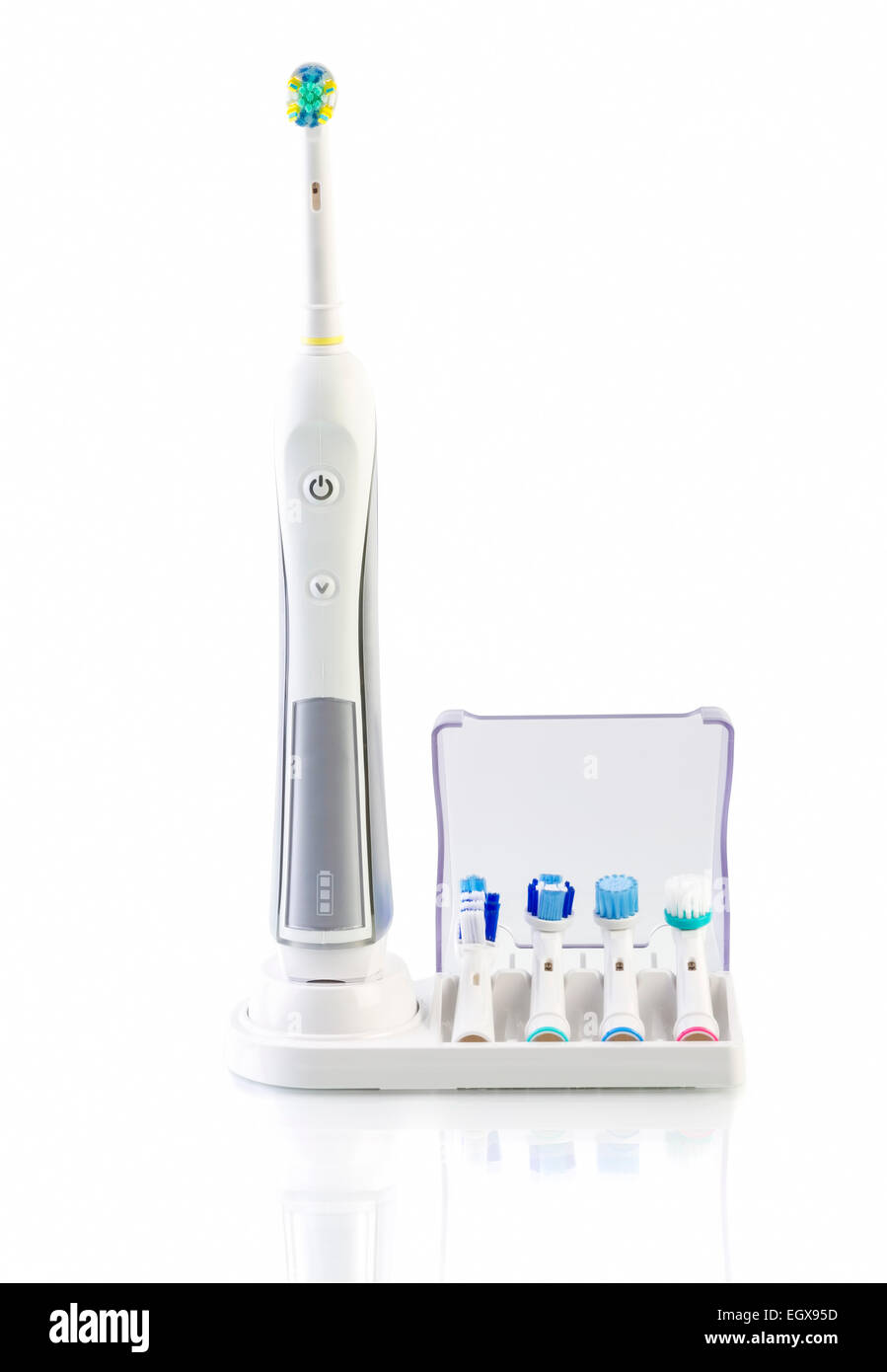 Cepillo dental eléctrico con soporte cargador y cuatro cepillos de repuesto sobre fondo blanco. Foto de stock