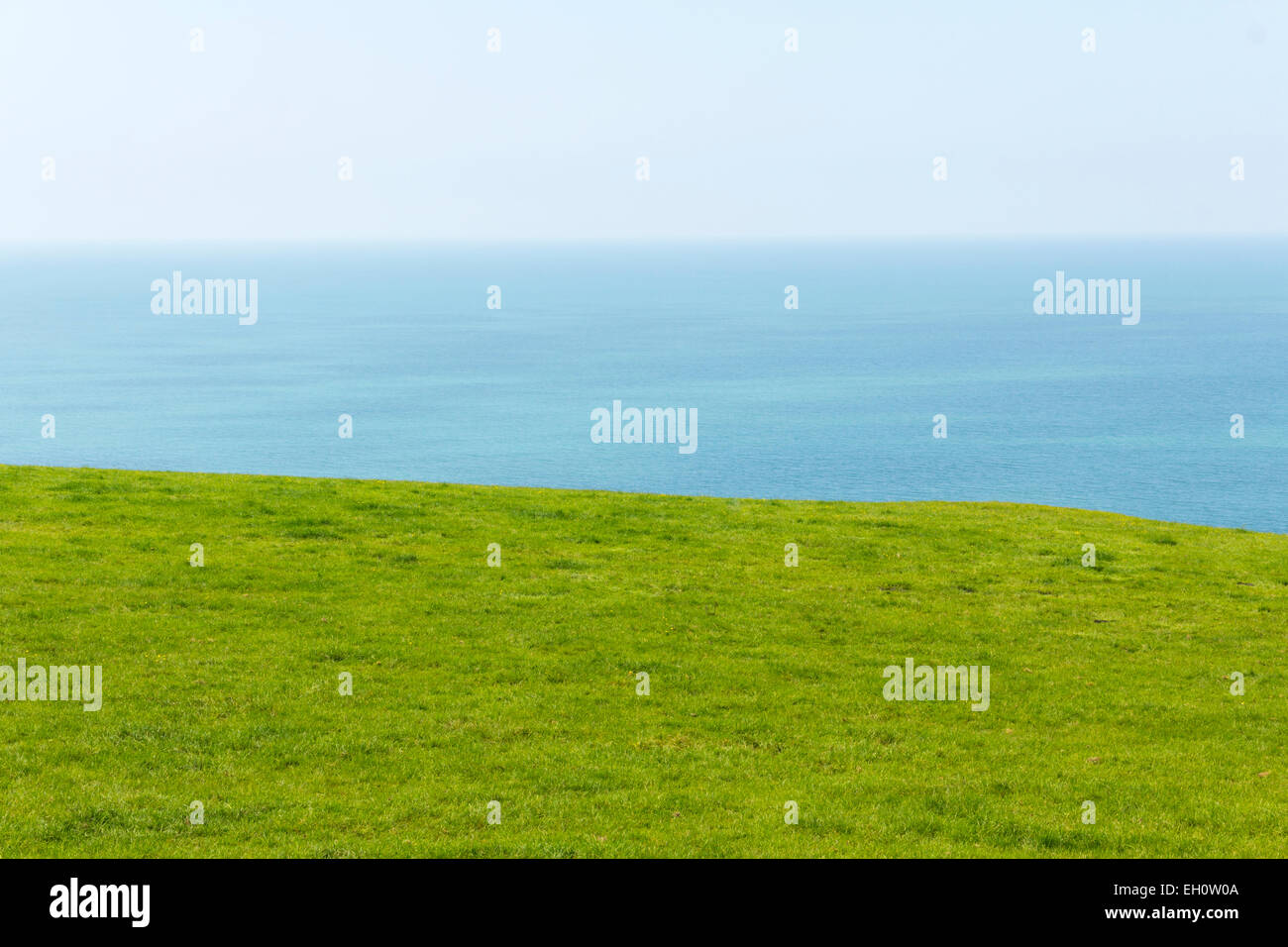 Horizontes de campo de hierba verde con vistas ligeramente ondulado mar y cielo blanco nebuloso. Costa oeste de Gales. Foto de stock