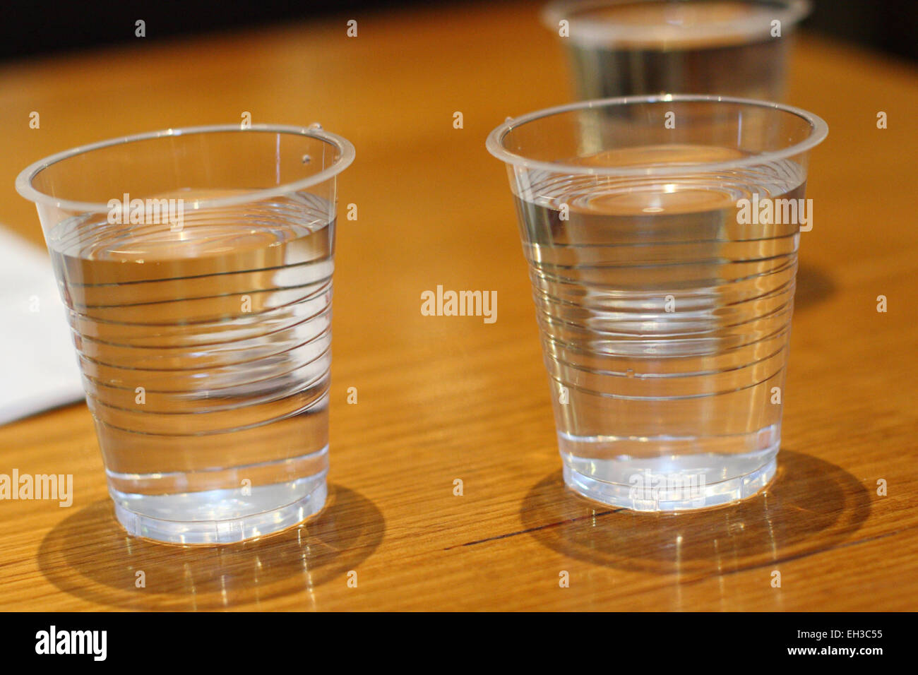 3 vasos de agua en vasos de plástico sobre una mesa de madera Fotografía de  stock - Alamy