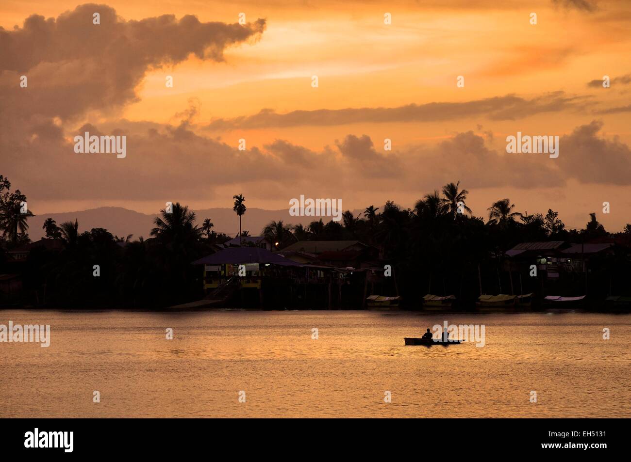 Malasia, Borneo, Sarawak, Kuching, silueta de pescadores en un barco sobre el río Sungai Sarawak al atardecer Foto de stock