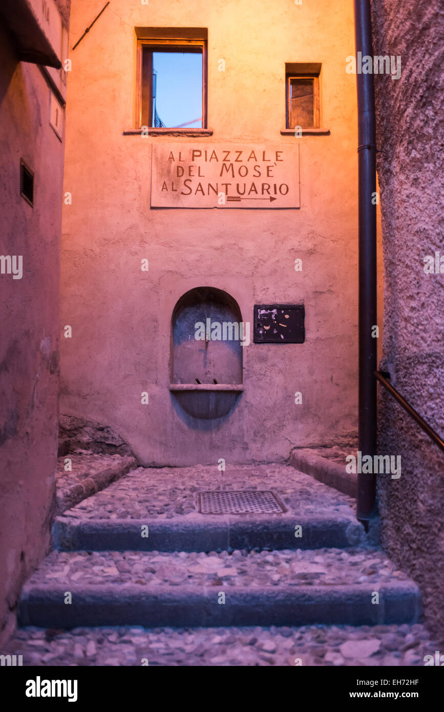 Colorida arquitectura, calles estrechas con pasos y fuente pública,en Santa María del Monte, Varese, Italia illminated al atardecer Foto de stock