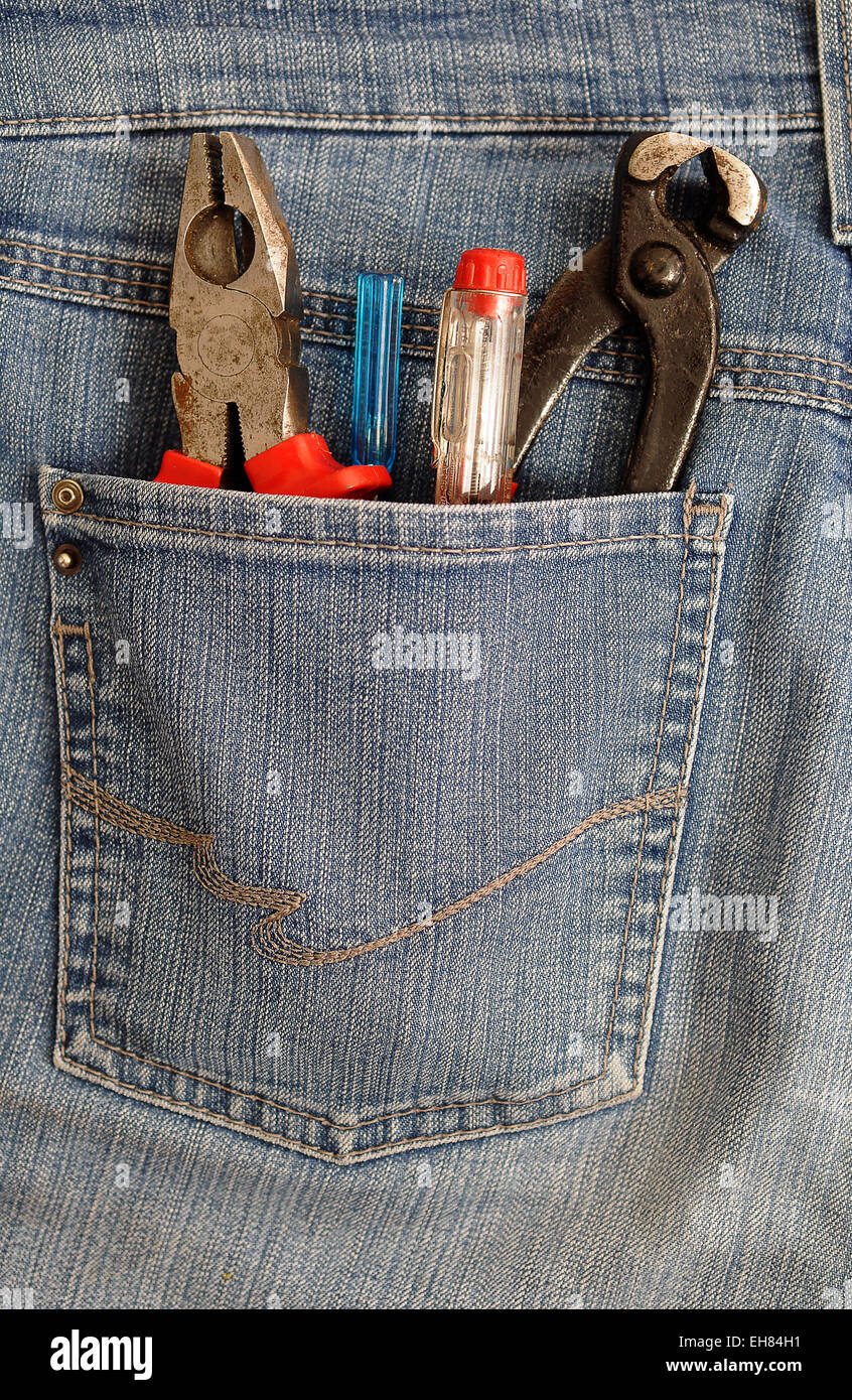Alicates y destornilladores en un bolsillo trasero, bricolaje Foto de stock
