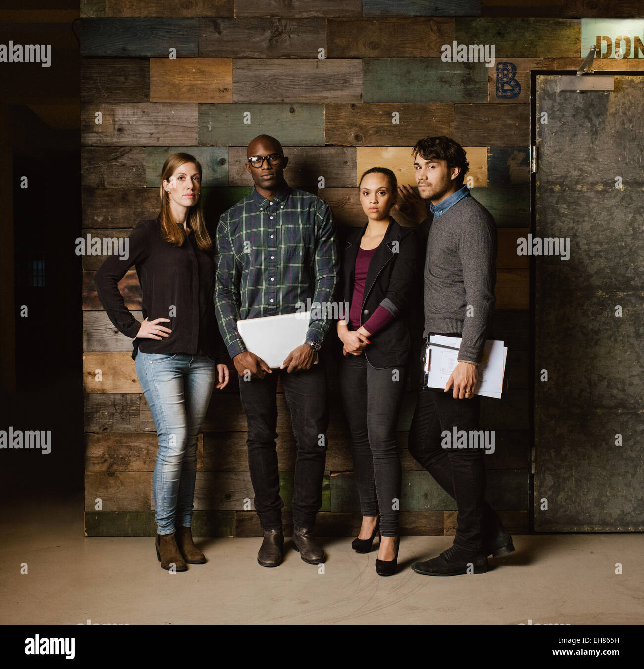 Imagen de longitud completa del equipo creativo multirracial posando para la cámara en la oficina. Jóvenes empresarios juntos contra un wo Foto de stock