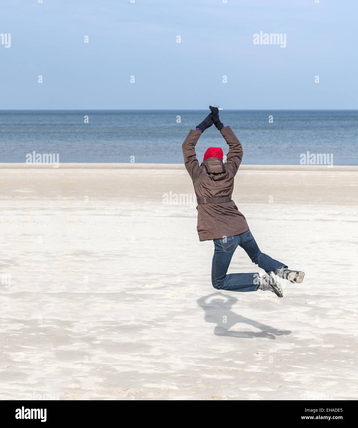 Mujer saltando sobre la playa, invierno activo concepto de estilo de vida, espacio para el texto. Foto de stock