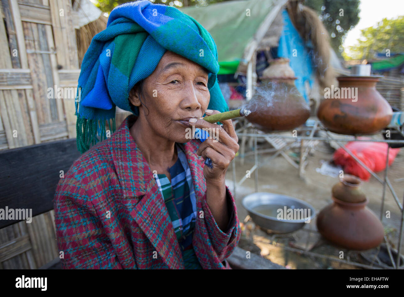 Mujer fumando un cheroot birmano en su choza en la playa Mingun en Mandalay, Myanmar Foto de stock