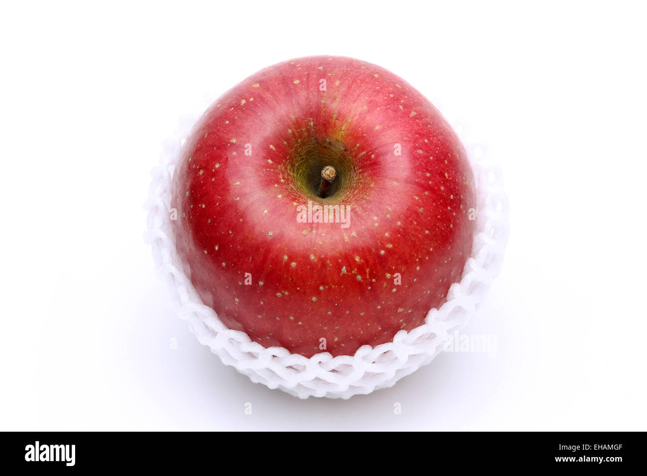 Manzana roja con embalaje net sobre un fondo blanco. Foto de stock