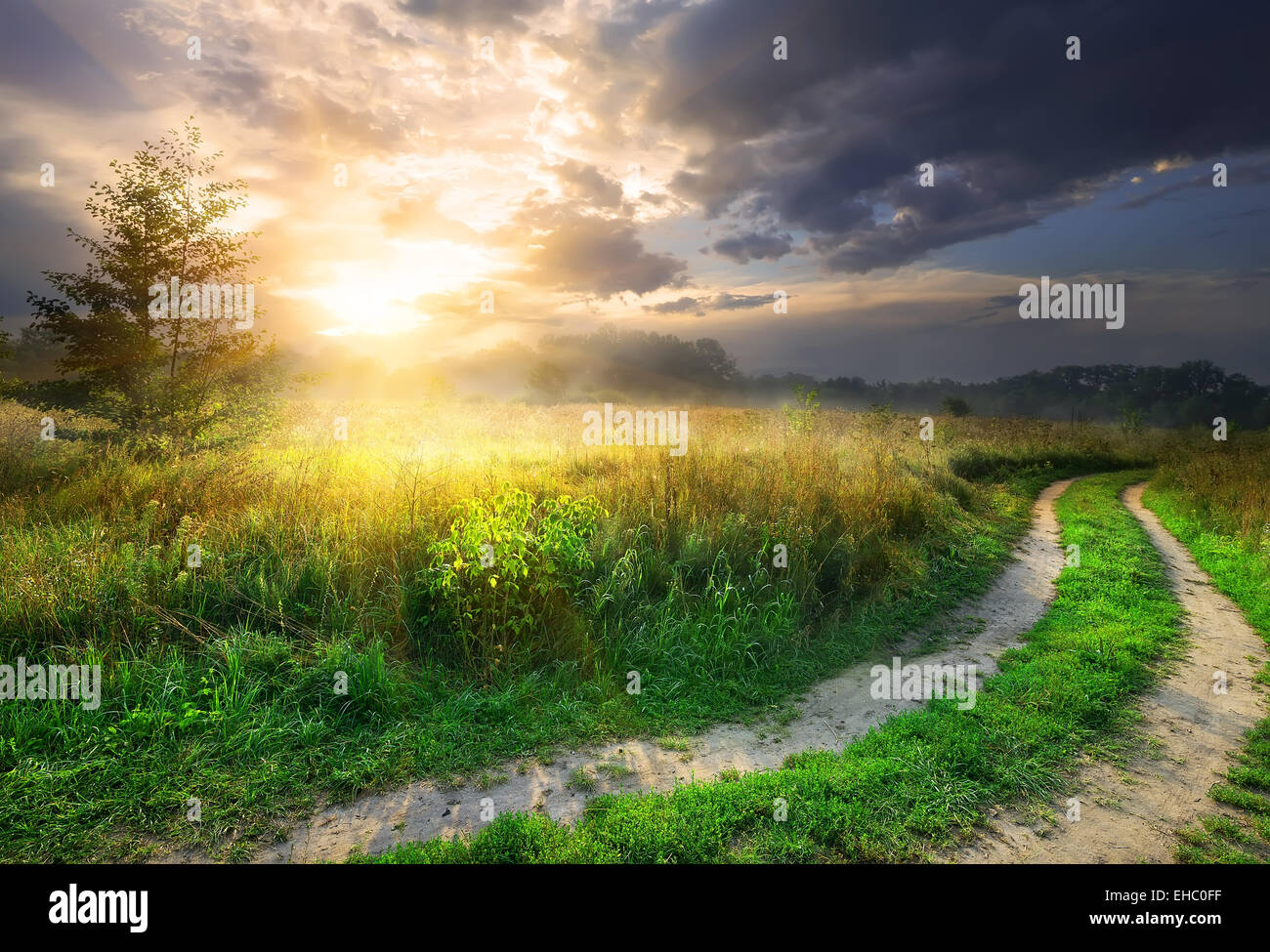Sol y nubes grises a lo largo de country road Foto de stock