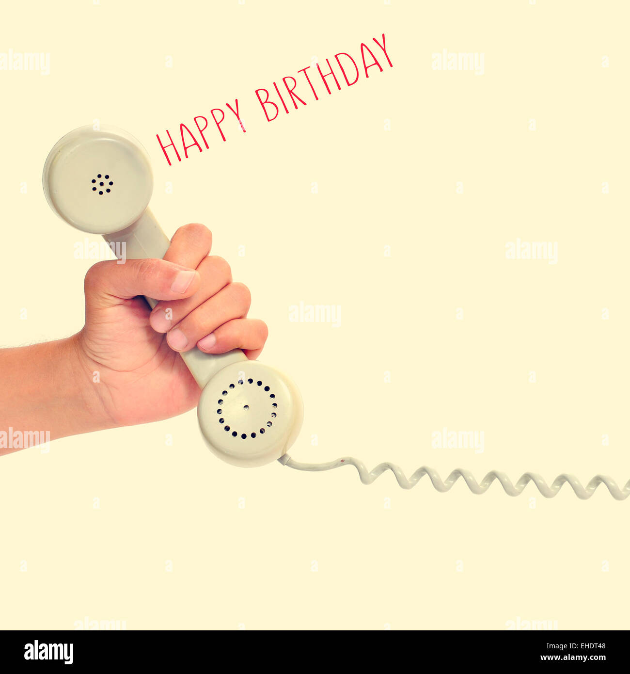 enfermedad realce Saludar La mano de un joven hombre sujetando el auricular de un teléfono retro y el  texto "feliz cumpleaños" en un fondo de color beige, con un retro  Fotografía de stock - Alamy
