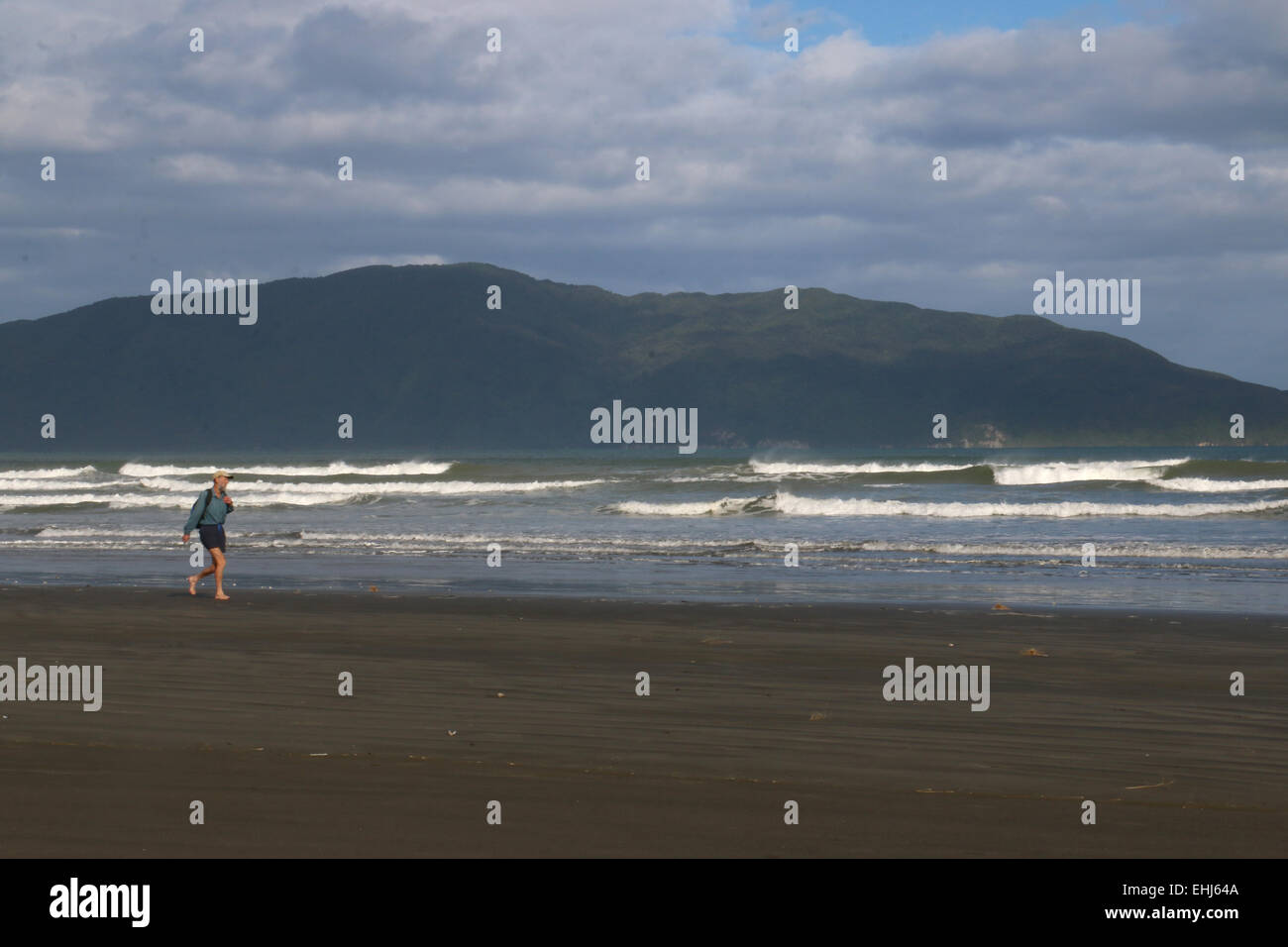 Los ciudadanos senior trotar en Waikanae playa cruzando la Isla Kapiti en fondo, Nueva Zelanda Foto de stock