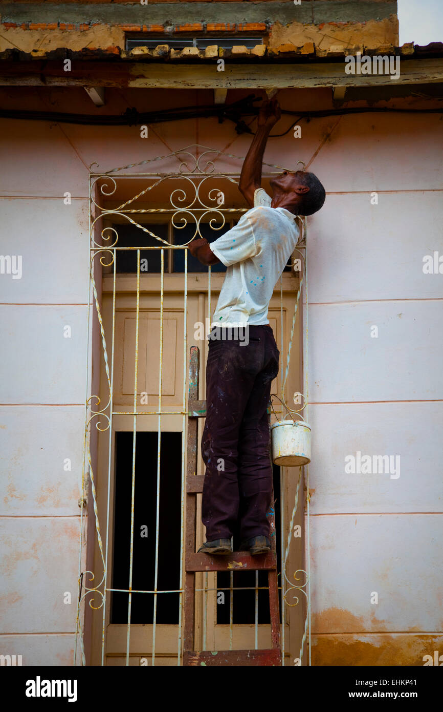 Un hombre repara un edificio desmenuzable en Trinidad, Cuba Foto de stock