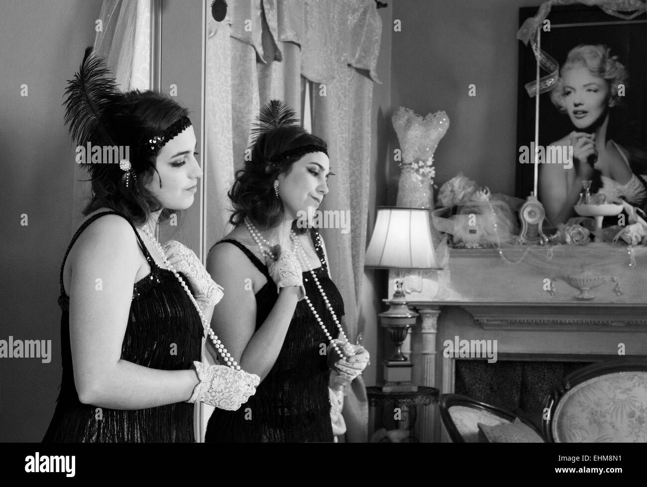 Señorita vistiendo ropa vintage en pensamiento profundo con el reflejo en el espejo y una foto de Marilyn Monroe en blanco y negro Foto de stock