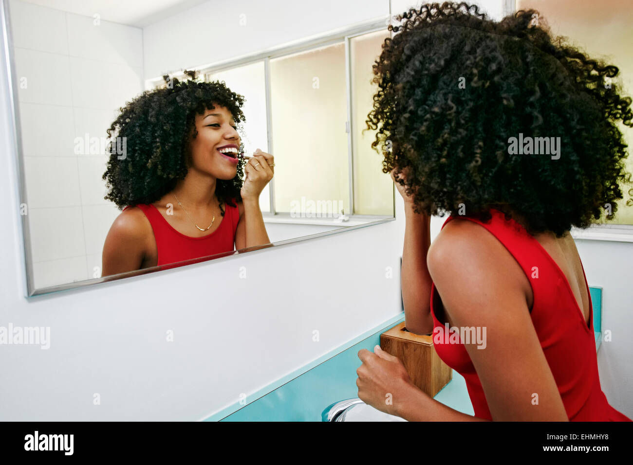 Mujer de raza mixta al maquillaje en espejo Foto de stock