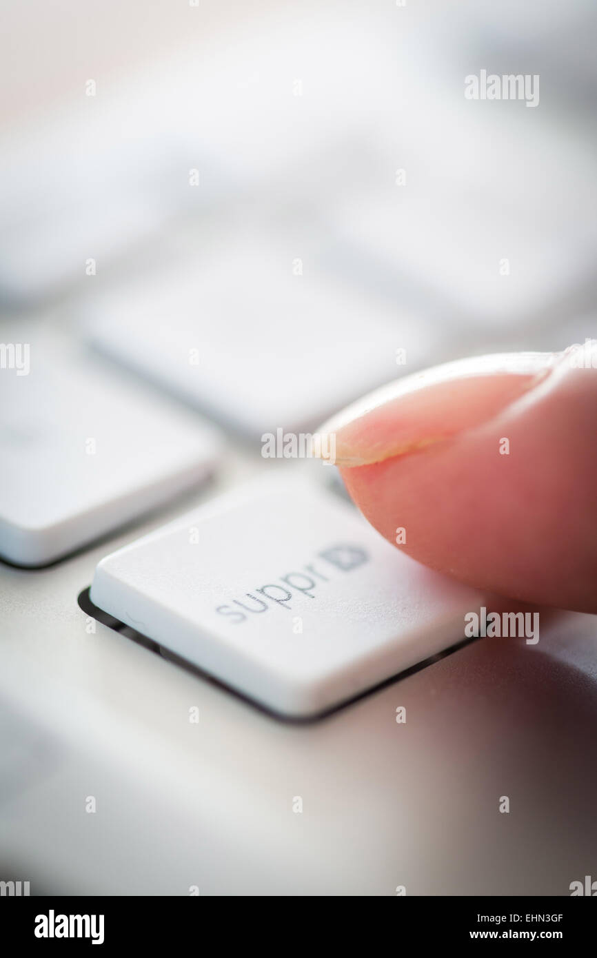 Mujer al pulsar un botón en un teclado de ordenador. Foto de stock