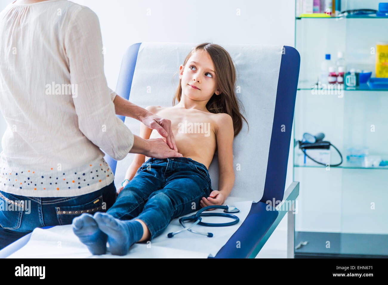 Médico examina a una niña en el abdomen. Foto de stock