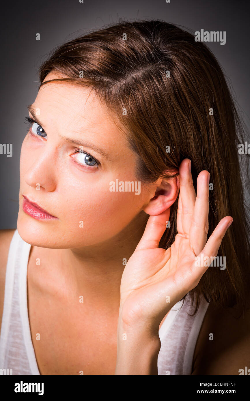 Mujer sosteniendo la mano a su oído. Foto de stock