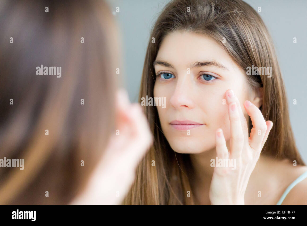Mujer comprobando su rostro en el espejo. Foto de stock
