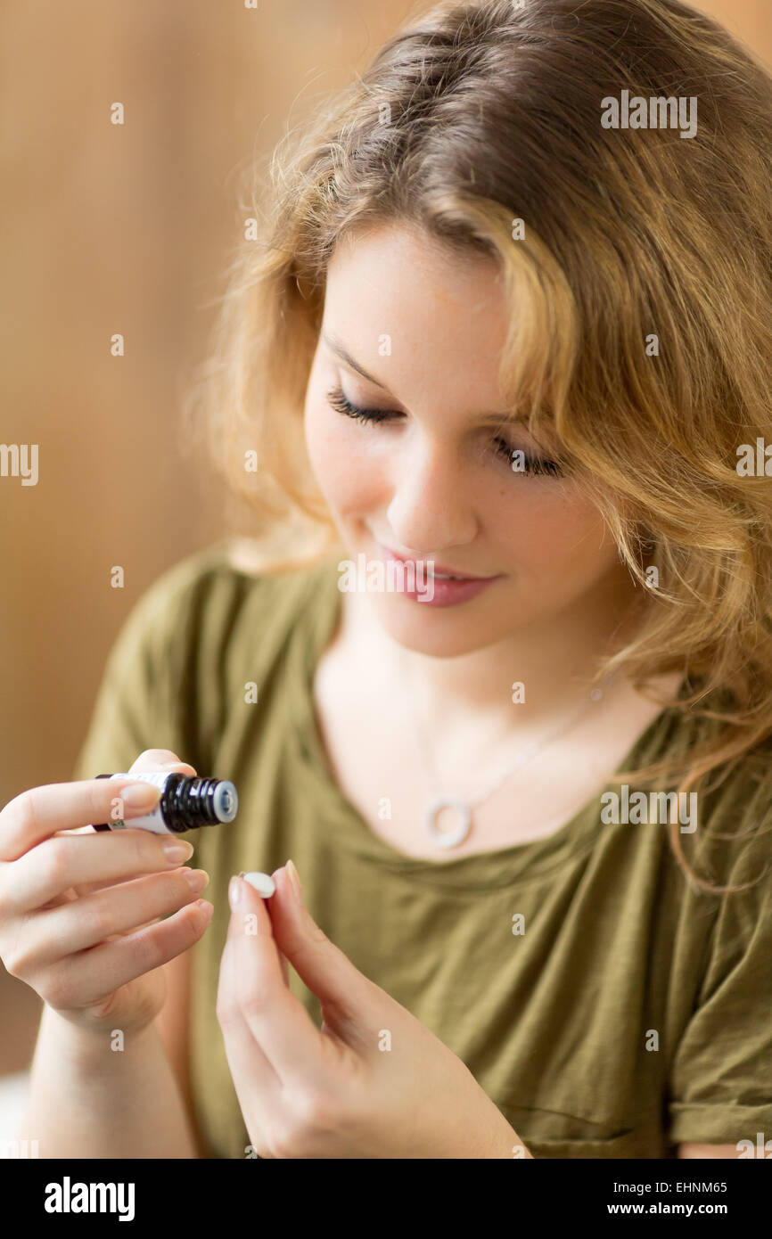 Mujer aplicar aceite esencial sobre una píldora neutral. Foto de stock