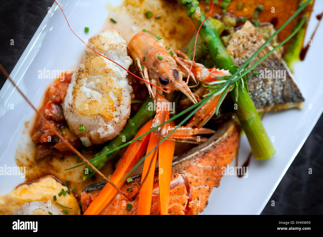 Plato con crustáceos, pescados, verduras y salsa Foto de stock