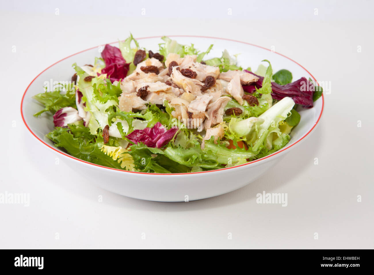 Ensalada de Pollo con salsa de tomate y las pasas en un recipiente blanco. Aislado sobre fondo blanco. Foto de stock